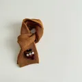Detail view of caramel knitted scarf with cute teddy bear accent and ribbed texture - Camel