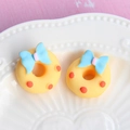 Macro shot of yellow resin donuts with blue bows and red dots on white ceramic - Large Bow - Yellow Base + Blue