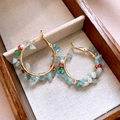 Detailed shot of golden hoop earrings with colorful stones and pearls in a wooden box - Bohemian Crushed Stone Wrapped Hoop Style
