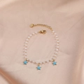 Elegant gold pearl bracelet with light blue star pendants on a satin background - Pearl Light Blue Three Stars