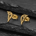 Detail shot of golden butterfly wing earrings with cut-out design on stone background - Gold Wings