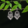 Detailed view of silver ethnic tassel earrings with geometric patterns on a wooden branch - E4961 (Spiral Round Piece)