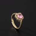 Macro detail of golden halo ring featuring a round pink zircon with adjustable open band - Round Halo Style