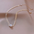 Elegante gargantilla de hojas doradas con perla blanca sobre fondo de seda beige - Dorado