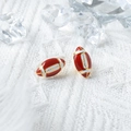 Dettaglio macro degli orecchini a lobo da rugby rosso e bianco su tessuto bianco - Stile rugby (JY-E1619-02)