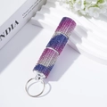 Close-up of a three-section gradient rhinestone pill bottle keychain on a white desk - Colorful Purple