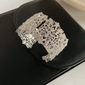 Makroaufnahme einer silbernen Filigran-Manschette mit kompliziertem hohlem Blumenmuster - Silber