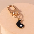 Vintage Tai Chi Yin Yang keychain with black pendant and gold metal ring on stand - Black