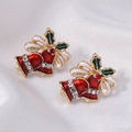 Macro shot of festive Christmas bell stud earrings with enamel holly leaves and red rhinestones - Golden Christmas Bell with Bow