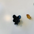 Top view of a small black bunny ear hair claw clip with bow shape on a white surface - Bright Black