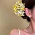 Detail view of yellow and white floral hair clip worn on a side bun vacation hairstyle - Duckbill Hair Clips / Yellow