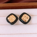 Close-up of black and gold square acetate earrings with gold-plated metal texture - Black