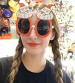 Close-up of novelty Christmas glasses featuring dual Santa Claus decor on orange frames - Oval Santa