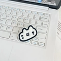 Detailed macro view of white plush cartoon cat embroidery patch on a laptop keyboard - Cat Head