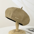Detailed macro view of camel suede beret featuring a signature gold metal logo plaque - Suede / Khaki