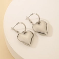 Macro detail of high-shine silver heart hoop earrings on a minimalist white platform - 3D Heart Shape / Silver