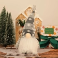 Detailansicht grauer Weihnachtsgnom mit Schneeflockenmütze vor festlichem Hintergrund - Grau