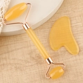Detail of honey-yellow resin facial roller and heart-shaped gua sha tool on a wooden surface - Resin Roller Transparent Yellow