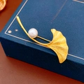 Dettaglio macro della spilla a foglia di ginkgo dorata con venature e perla bianca - Oro (Placcato Oro Vero)