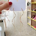 Elegante goldene lange Wellen-Spiral-Ohrringe an einer weißen Schmuckkarte hängend - Wellen Quaste Ohrfädel / Gold