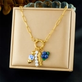 Détail du collier doré avec pendentifs poisson, bleuet et perles sur une boîte beige - Style Perlé Poisson Rouge Myrtille Perle(N3732)