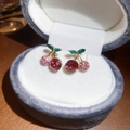 Gros plan de boucles d'oreilles cerise en cristaux rouges sur un écrin en velours gris - 67# Tige en Argent Or Rose Cerise