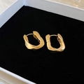Elegant gold twisted metal stud earrings presented in a black velvet jewelry box - Irregular Ear Cuffs / Gold