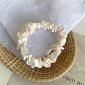 Elegant beige satin hair scrunchie with a glossy silk-like texture on a rustic tray - Milk White