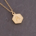 Minimalistische gouden ketting met zeshoekige hanger letter A op donkere achtergrond - Letter A (1#A)