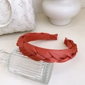 Braided orange hairband with twist texture and premium satin finish on glass vase - Brick Red