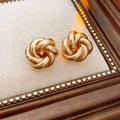 Macro di orecchini a fiore ritorto dorati su tessuto con cornice decorativa - Oro