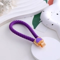 Dettaglio portachiavi in pelle intrecciata viola con ciondolo a cuore dorato lucido - Cordino in pelle viola