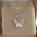 Détail d'un pendentif papillon argenté avec strass brillants et émail blanc élégant - Papillon