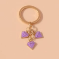Detail of golden alloy keychain featuring three purple enamel diamond pendants - Purple