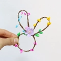 Makro-Detail des handgefertigten Osterhasen-Serviettenrings mit bunten Perlen und Blumen - Violette Blume Stil