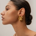 Golden textured flower earrings with minimalist metal wrinkles on female model - Gold