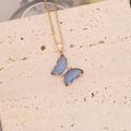 Macro d'un pendentif papillon bleu doré avec diamants posé sur un support en pierre - Bleu Saphir
