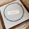 Flat lay of colorful beaded flower necklaces on a wooden tray with a greeting card - Blue-Brown
