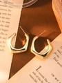 Macro shot of gold geometric earrings on vintage paper background with soft lighting - Gold Open Pentagon