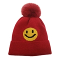 Détail d'un bonnet en tricot rouge avec un smiley jaune et un grand pompon en fourrure - M(54-60cm) / Bordeaux