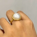 Dettaglio di una grande pietra bianco perla su un anello aperto dorato sulla mano - Anello con Perla a Mezza Sfera Grande Oro (K715)