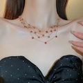 Close-up of four-layer gold chain necklace with red round zircon stones on model's neck - Gold Layered Red Round Necklace