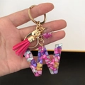 Macro shot of resin letter W keychain with colorful stones, pink tassel and glitter ball - Small Ball Tassel Clasp / Letter W