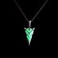Macro shot of silver arrow pendant with glowing green fluorescent core on black background - Green