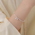 Elegant silver bamboo-style chain bracelet with two small bell charms on a female wrist - Bamboo Bell Style (SL1094)