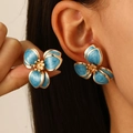 Detalle de pendientes de flor azul con borde dorado usados en la oreja de la modelo - Pendientes de botón (03 Pendientes Azules A-992) / Azul