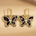Elegante Schmetterlingsohrringe aus Gold mit Leoparden-Acetat auf beigem Lederhintergrund - Ohrclip-Schwarz