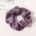 Close-up of a premium purple silk satin scrunchie with soft folds and elegant glossy finish - Grape Purple