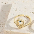 Close-up of gold adjustable evil eye ring with blue center and pavé zircon accents - Heart Fish Tail Ring