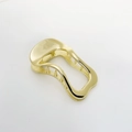 Dettaglio della molletta dorata irregolare con denti metallici interni e trama lucida - Oro